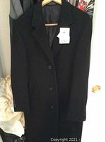 Black Chaps wool coat hanging on hanger, buttoned with a tag 057.