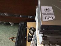 Remote controls on carpet with part of wooden furniture visible.