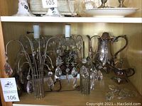 Shelf with two wall sconces with crystal prisms and silver plated coffee set pieces on the right