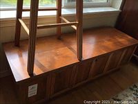 Lane cedar chest with a wooden bar stool placed upside down on top, showing the chest's surface condition and size.
