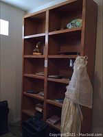 Full view of double wide light oak bookcase with items on shelves, showing size and appearance.