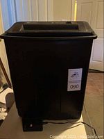 Black rectangular Fellows PS 40 shredder with top slot, power cord attached, sitting on floor near door.