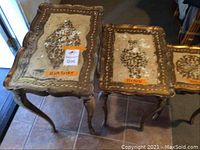 Set of three decorative nesting tables showing top views with worn gold accents and patina
