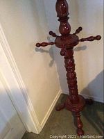 Full view of teak coat rack showing top and mid level spindles, polished dark wood finish.