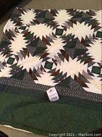 View of the quilt spread out showing the geometric and floral patchwork design in dark green, burgundy, cream colors.
