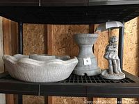 Photo of concrete bird bath with scalloped edge and pedestal base along with decorative figurine of girl with umbrella