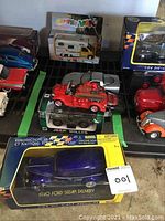 Photo showing multiple die-cast model cars including the camper van in original box, Jeep Willys, and other loose models including a red vintage fire truck.