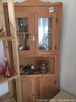 Front view of pine and cedar wood corner cabinet showing glass upper doors and solid lower doors.