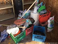 Overview of garden lot including crates with plant pots, watering can, and bags of potting soil in a shed.