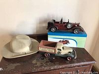 Lot with wooden roadster-style car, original box, wooden decorative truck, and felt cowboy hat.