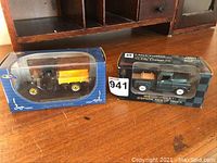 Two collectible model trucks displayed in original packaging on a wooden surface