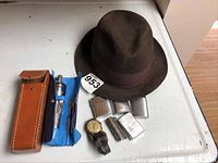 Overview of all items showing hat, lighters, wristwatch, and toolkit on white surface