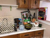 Overview of various garden-related items including planters, hand tools, spray bottles, and an umbrella table screen, arranged on a kitchen counter.