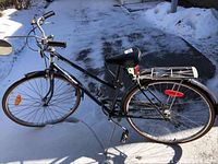 Side view of black Free Spirit ladies bicycle with step-through frame, front and rear fenders, rear rack, and 3-speed gearing.