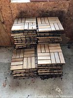 Stack of wood decking tiles showing top view of parquet pattern and plastic bases beneath