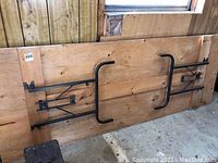 Underside of tabletop showing black metal folding legs attached and screws.