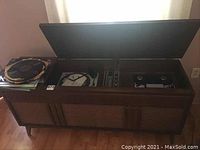 Full view of the entertainment console with top lids open showing record player, radio, and reel to reel tape recorder. Stack of records shown to the left side of the console.