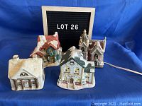 Four ceramic Christmas village buildings on blue background, includes school, two houses, and church, marked Lot 26