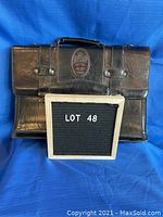 Front view of black leather briefcase showing Heys Canada embossed patch and handle