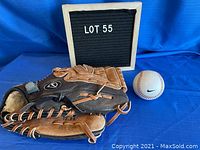Photo showing Nike leather baseball glove model KDR 1200 with separate Nike baseball against blue background.