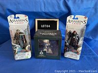 Three unopened Assassins Creed figures: Blackbeard and Haytham Kenway in blister packs flanking a Lootcrate Assassins Creed Origins Bayek figure in a cardboard display box.