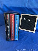 Front view of three Hunger Games books in black display case showing spines with titles and author Suzanne Collins.