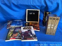 VHS tapes and Star Wars paperback books arranged on a blue surface with a sign that reads 'LOT 70'.