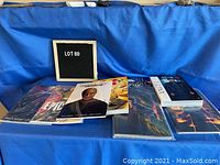 Lot of 7 graphic novels arranged on a blue cloth surface, showing various titles and covers