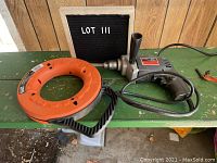 SKIL 597 electric drill and Klein Tools Depthfinder fish tape laid out on a green bench with LOT 111 board visible.