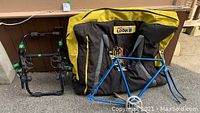 Photo showing the bike carrier rack, bike frame, and the LOOK travel bike bag stacked outside on pavement.