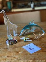 Full lot arrangement on wood surface showing clear giraffe, blue dolphin, dragonflies, hummingbird, and castle base