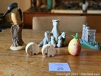 Wide shot of entire collection on wooden table including kingfisher, elephants, castle, stone pieces, and pineapple