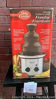 Front view of original packaging box showing product image, brand Betty Crocker, and key features of the chocolate fondue fountain.