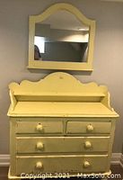 Front view of the pale yellow painted vintage wood dresser with upper shelf and matching mirror above