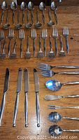 Close-up of assorted flatware pieces including spoons, forks, knives and service pieces.
