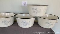 Four cream colored porcelain tin bowls stamped with 'Fresh Towel' placed on a gray surface.