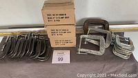 Array of gray powder-coated C-clamps with two cardboard boxes labeled Part No:57-2620-8 (6 pcs each)