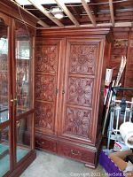 Front view of Lane wooden armoire with ornate carved doors and two lower drawers, showing condition and size relative to nearby objects.