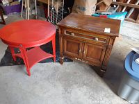 Photo showing red round side table and brown rectangular nightstand placed side by side on a concrete floor with visible wear and scratches