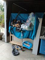 Full lot view showing guitars, stuffed animals, razor scooter, wooden duck toy, pool sticks, and hard hat on a wooden shelf.