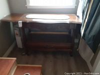 Wooden entry table from front showing carved details and lower shelf.