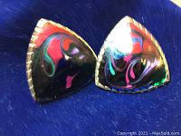 Close-up front photo of a pair of triangular earrings with black, red, purple, and green abstract design.