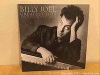Front cover of the Billy Joel Greatest Hits Volumes I & II album featuring black and white photo of Billy Joel leaning on a piano.
