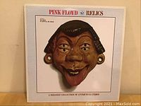 Front cover of Pink Floyd 'Relics' album featuring a 3D mask with three eyes and a tongue sticking out.