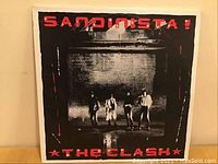 Front cover of The Clash's Sandinista! 3 LP album in red and black with band members.