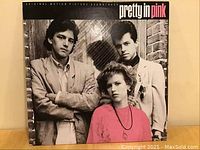 Front cover of Pretty in Pink original motion picture soundtrack showing actors in 80s attire, black and pink text logo.