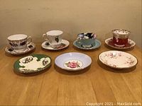 Overview of four matched cup and saucer sets at back and three loose saucers at front on tabletop