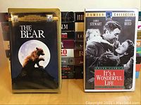Photo showing two VHS tapes "The Bear" and "It's a Wonderful Life" with cover art and cases.