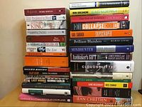 Two stacks of assorted fiction and non-fiction books arranged vertically showing spines and covers with titles and author names.