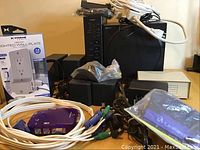 Photo showing cables, KVM switch device, and packaged electrical wall plate alongside the audio equipment.